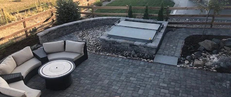 Custom outdoor paver patio with seating wall and gas fire pit in Fort Collins, CO.